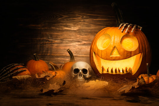 Carved and whole pumpkins for Halloween and skull on dark wooden background