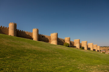 Fototapeta na wymiar Wall of Avila with clear blue sky and wide lawns