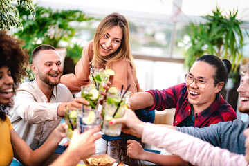 Young friends toasting mojito drinks at rooftop cocktail bar - Party time concept with...