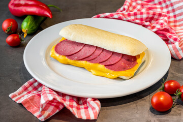 Sandwich with salami and cheddar on dark stone table
