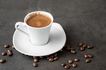 Turkish coffee over smoke and coffee beans on dark stone table