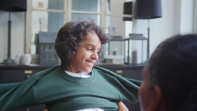 Slow motion of mother helping boy put on school jumper