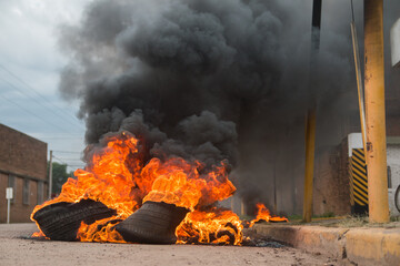 Dramatic shot of burning tires with black smok in the middle of the street © Leo Lascher/Wirestock