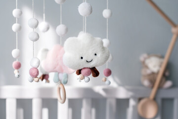 Baby crib mobile with smiling clouds and snow. Kids handmade toys above the newborn crib. First...