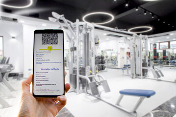 hand showing green covid certificate before entering a gym