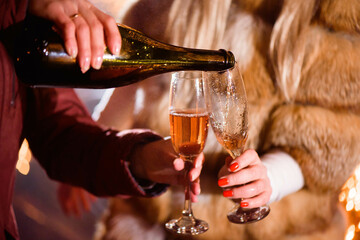 Pouring champagne into glass at party, close up, winter