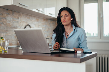 Businesswoman using airpods and a laptop while working from home