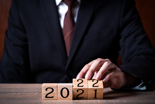 businessman holding wooden block and 2022 new year goal change from 2021 with copy space for text.