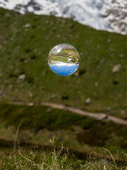 Glass ball floating over pasture in the alps