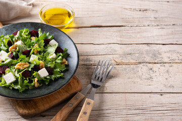 Beetroot salad with feta cheese,lettuce and walnuts on rustic wooden table. Copy space