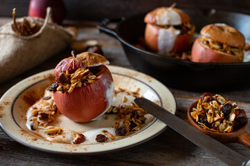 Breakfast cereal with baked apple filled with granola and served with yogurt and cinnamon topping