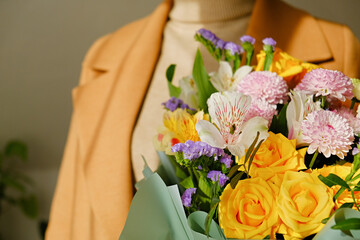 A woman in a beige coat holds a beautiful autumn bouquet in her hands. Depersonalization concept. Close up.