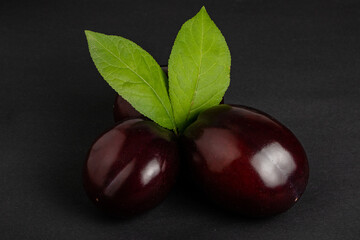 Plums with plum leaves on a dark background.