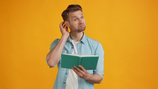 Cheerful clever thoughtful guy read book imagine ideas look empty space