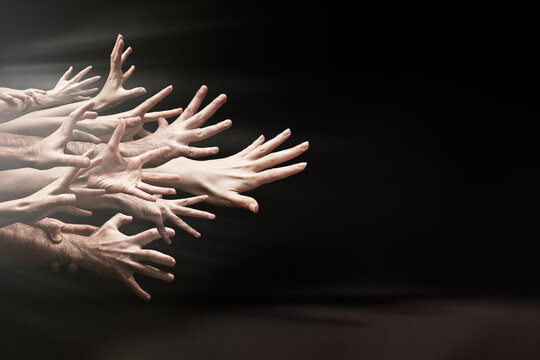 A lot of hands aggressively reaching forward. Black background. Copy space. The concept of bullying, psychology and social relations