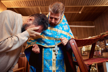 a man repents of his sins, confesses with a priest in the Orthodox church