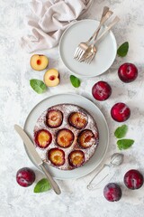 Tasty cake with plums on light background. Top view. Copy space.