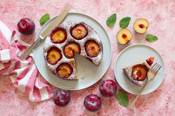 Tasty cake with plums on light background. Top view. Copy space.