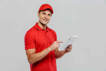 Young delivery man using and pointing finger at tablet computer