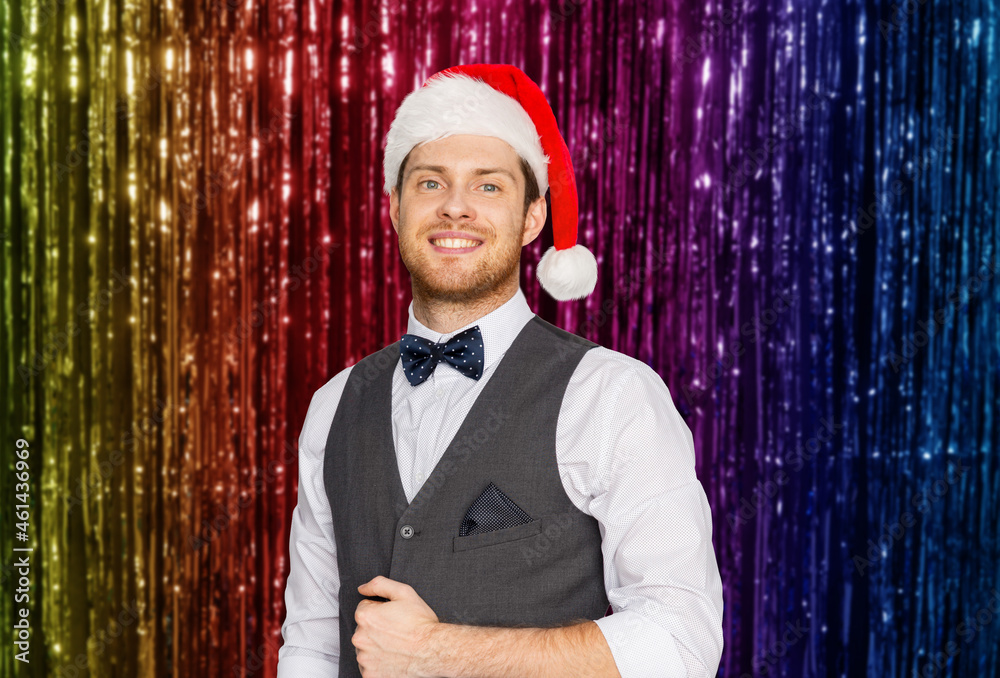 Sticker celebration, people and winter holidays concept - happy man in santa hat and suit at christmas party over foil fringe on background