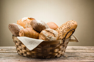 assortment of baked bread in straw basket on wooden table