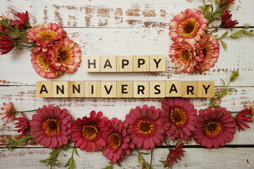 Happy Anniversary alphabet letter with flower decoration on wooden background