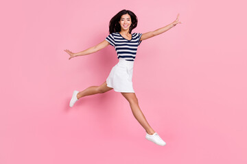 Photo of funny adorable young lady dressed striped clothes smiling jumping high empty space...