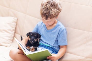 A boy with a little dog is reading a book - 461441977