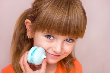  Beautiful little girl holding a blue sweet dessert macarons in her hands portrait close-up, sweet pastries happy childhood childish emotions, selective focus