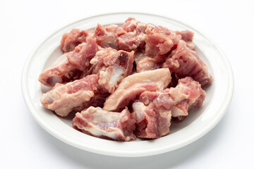 Raw pork ribs in white plate on white background.