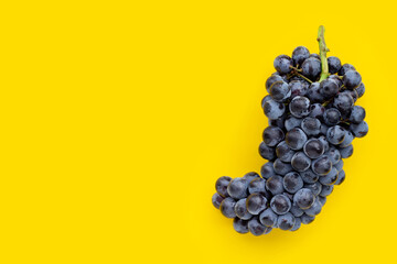Fresh black grapes on yellow background.