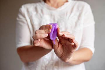Close up of woman hand folding menstrual cup showing how to use. Women's health and alternative hygiene, zero waste alternatives, female intimate hygiene period products, critical days.