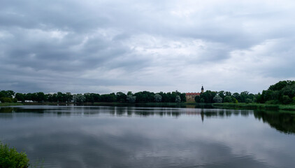 Fototapeta na wymiar Beautiful clouds are reflected in the lake overlooking the ancient castle of the Radziwills in Nesvizh, Belarus. Summer landscape with architectural elements.