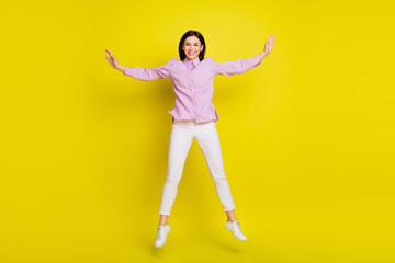 Fototapeta na wymiar Full length photo of hooray brown hairdo young lady jump wear pink shirt pants isolated on yellow color background