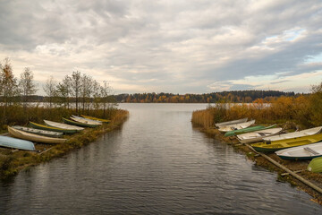View of the river mouth with rowboats on the bank. Autumn Finnish landscape with a lake and cloudy sky