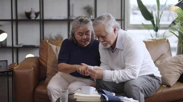 Asian elderly couple using oxygen pulse fingertip for test oxygen to the wife in the house