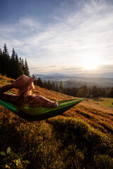 Woman hiker resting after climbing in a hammock at sunset - 461445166