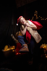 A cheerful dwarf with big red bag at home. Assistant of Santa Claus in a red hat and with glowing...