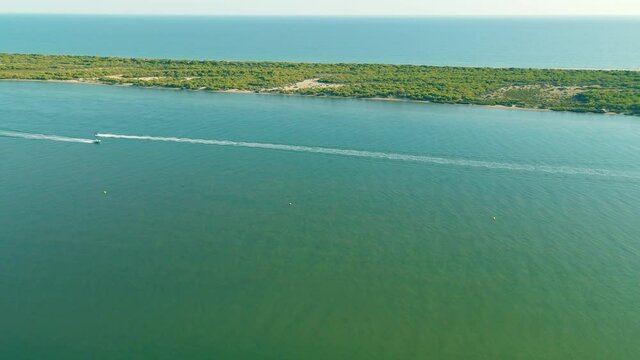 Arial view of People Riding or Driving Hydrocycles near Playa Flecha Nueva Umbria - Spit Separating Piedras River from Atlantic Ocean daytime on sunny day, Huelva, Andalusia, Spain

