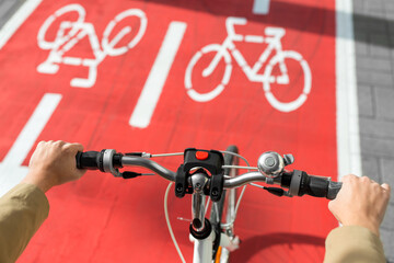 traffic, transport and people concept - close up of hands with bicycle's wheel on red bike lane on city street