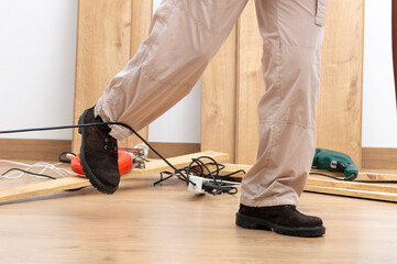 Close up of a carpenter legs stumbling with an electrical cord at home