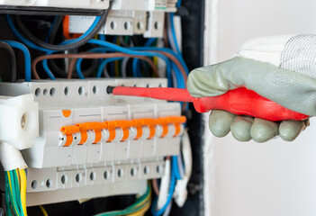 Closeup of electrician engineer works with electric cable wires of fuse switch box. Electrical...