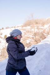 Fototapeta na wymiar Young woman in the snow mountains landscape on holiday holding natural soft white snow in her hands