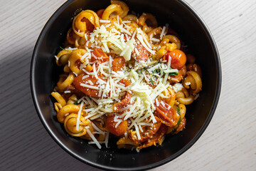 A bowl of pasta topped with shredded cheese.
