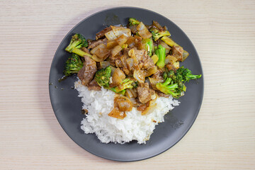 A plate of beef and broccoli stir fry with steam rice.