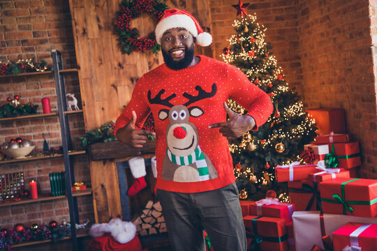 Photo of cheerful happy afro american man point finger sweater christmas deer indoors inside house home apartment