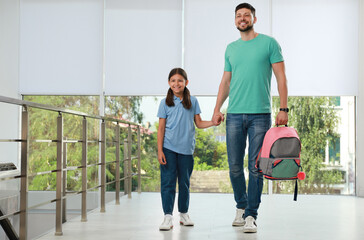 Father with his little daughter in school hall