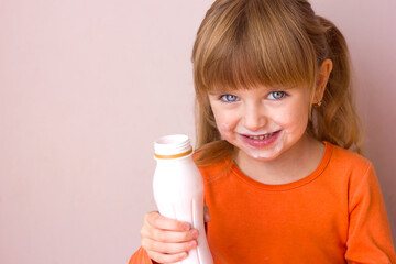 Portrait of a little beautiful girl with emotions on her face, her mouth stained with milk, holding a plastic bottle with a milk drink, yogurt or kefir, selective focus