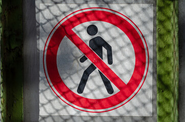 A sign prohibiting access to the fence. Gray fence with a red an