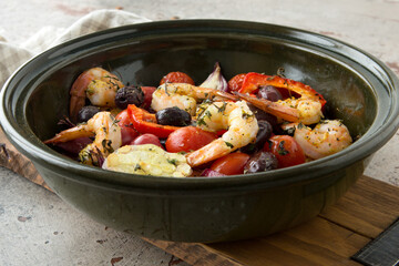 round baking sheet with baked shrimps with vegetables on the table